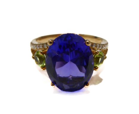 A fine yellow gold (marked '750 18K') dress ring centrally set with a brilliant-cut oval tanzanite flanked by two peridots to
