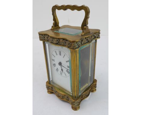 A late 19th to early 20th century French gilt-brass and glass-sided carriage clock: the shaped handle above foliate-style pie