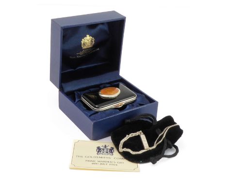 A modern boxed enamel 'toy': the hinged lid with amber enamel depicting a leopard, together with a silver ingot and chain, Go