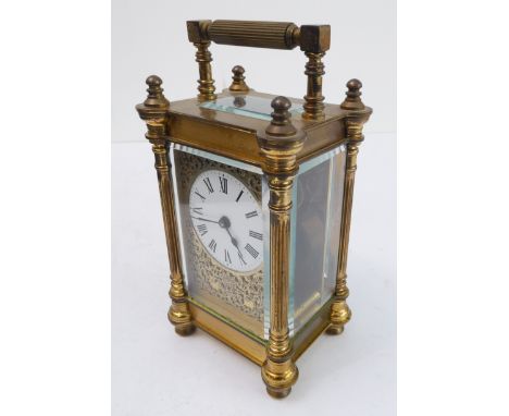 An early 20th century gilt-metal and glass-sided carriage timepiece: white enamel dial with Roman numerals within a scrolling