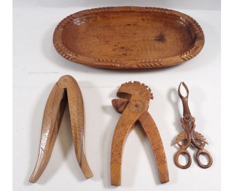 A carved wooden bread basket, 34.5cm, two wooden nut crackers and a pair of olive tongs