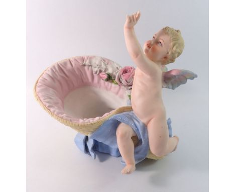 A 19th century French bisque cherub seated by a basket, 27cm tall