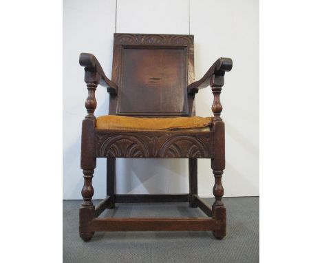 An 18th century oak Wainscote chair with a turned, carved crest, a panelled back, scrolled arms, baluster supports and leathe