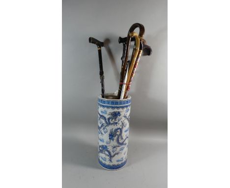 An Oriental Ceramic Cylindrical Stick Stand Decorated with Dragons Containing Six Walking Sticks etc, Stick Stand 47cm High 