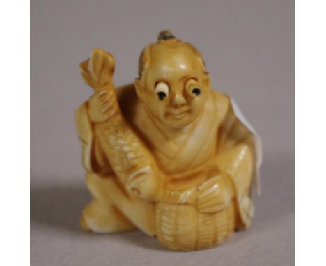 Antique Japanese ivory netsuke depicting a man holding a fish, signed to base, 4cm high approx. NB These may not be exported 