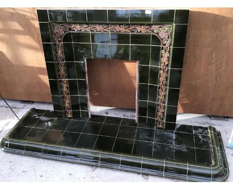 A GREEN TILED FIREPLACE SURROUND AND HEARTHWITH ORNATE GRAPEVINE DESIGN 
