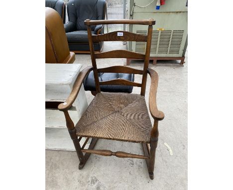 AN OAK LADDER BACK ROCKING CHAIR WITH RUSH SEAT 