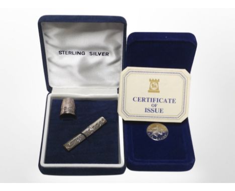 A silver thimble and needle case in box, and a further cased proof £1 coin with certificate.