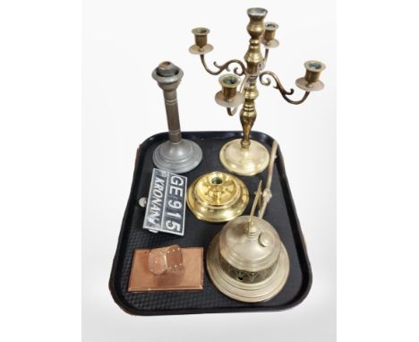 A group of metal wares including a die-topped paperweight, a brass squat candlestick, further brass candelabrum, etc.