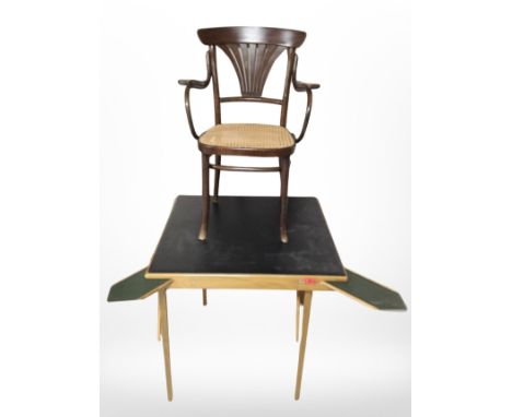 A black vinyl-topped square folding card table and a beech bergere armchair. 