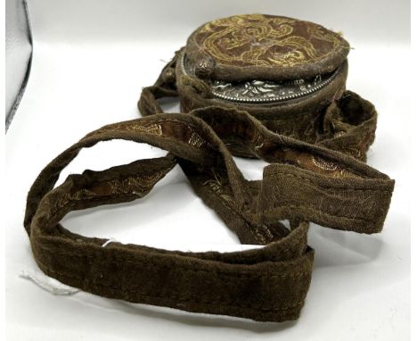 A Chinese silver coloured metal reliquary, with a glass panel inset with buddha, in an embroidered case, 10 cm wide