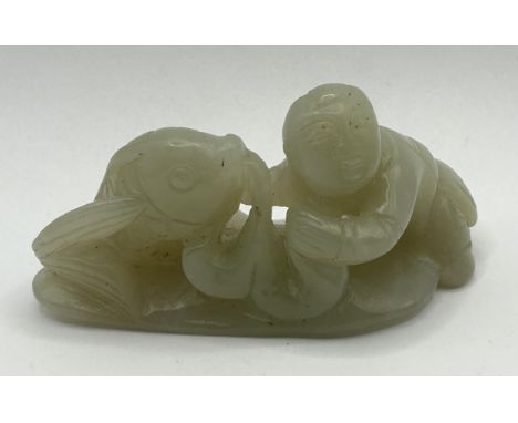 A Chinese carved green stone figure of a man with a fish, 8 cm wide