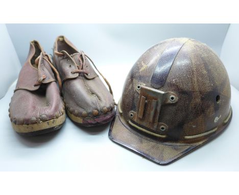 A small child's pit helmet, marked 'A Campbell Head Cradle' and a pair of clogs, marked 1945 and with government/military bro