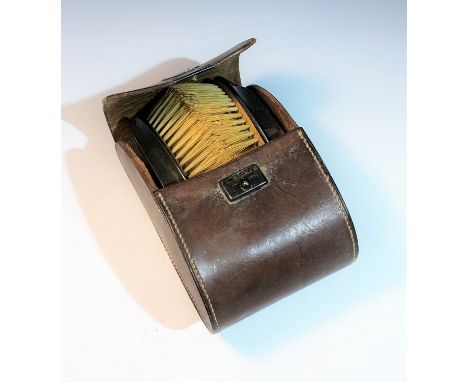 A pair of engine turned silver mounted brushes in a leather case with silver clasp and shield.