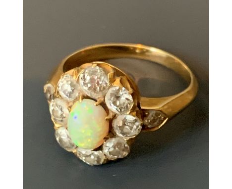 A gold ring with small oval opal surrounded by old cut diamonds and with diamond shoulders.