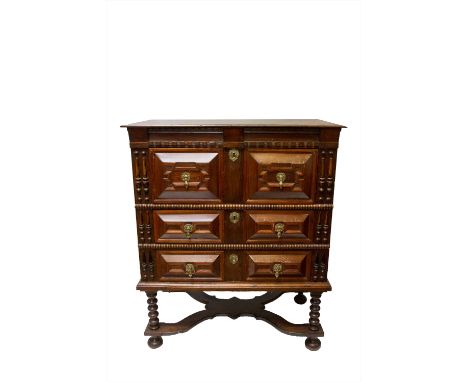 A 17th century oak chest on stand, with three long drawers on bobbin turned supports and bun feet, joined by a shaped stretch