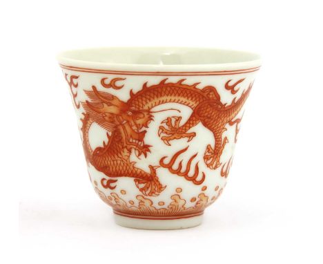 A Chinese iron-red cup,Tongzhi (1862-1874), of waisted form, painted with dragons chasing a flaming pearl above spuming waves