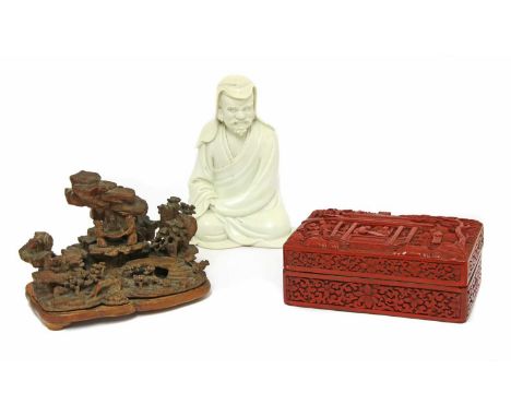 A Chinese blanc de Chine figure, 18th century, of a luohan, seated wearing a long robe with the folds spreading naturally to 
