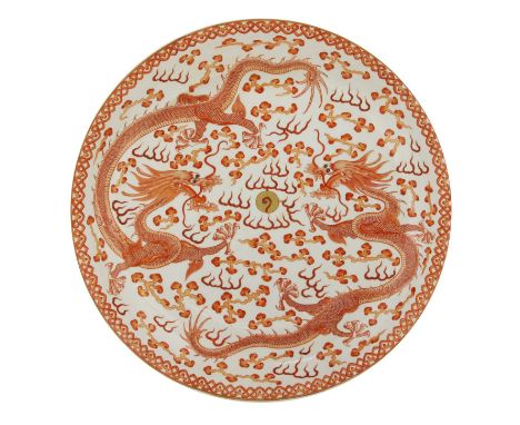 A Chinese iron-red charger,of circular form on a circular foot, painted with two dragons chasing a flaming pearl amongst clou