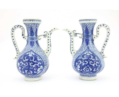 A pair of Chinese blue and white ewers,Kangxi (1662-1722), each of pear form with a loop handle and scroll spout attached to 
