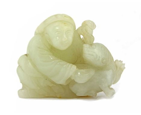 A Chinese jade carving, Qianlong (1736-1795), of a boy wearing a long robe and a winter hat, holding a brocade ball in his le