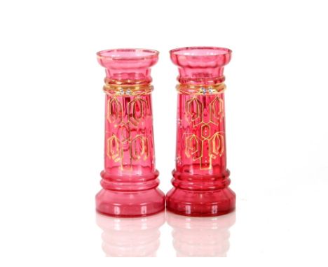 A pair of cranberry vases, with blue enamel floral decoration heightened in gilt, 23cm high