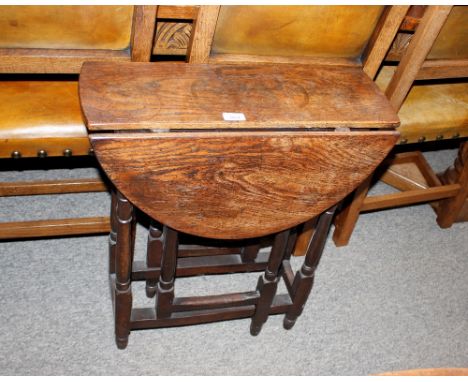An oak gate leg tea table, the rounded drop leaves raised on turned baluster supports, 60cm