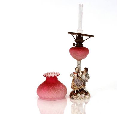 A 19th Century Volkstedt figure group table oil lamp,&nbsp;having red tinted opaque leaf moulded glass reservoir and shade&nb