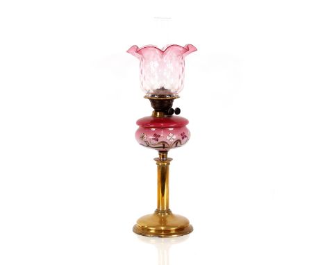 A Victorian brass oil lamp, having floral enamelled pink glass reservoir and tinted shade, 65cm high