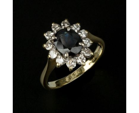 A sapphire and diamond cluster ring, the oval cut sapphire claw set within a surround of eight cut diamonds, approximately 0.