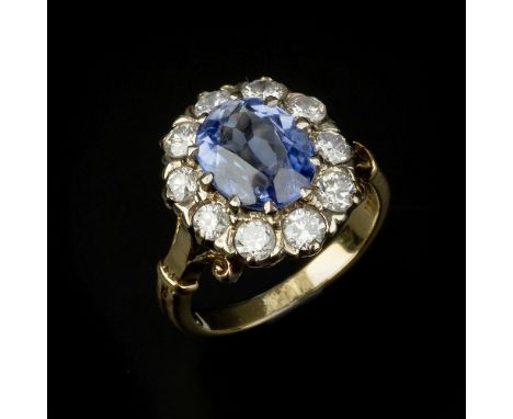 A sapphire and diamond cluster ring, the central oval cut sapphire claw set within a surround of brilliant cut diamonds, appr