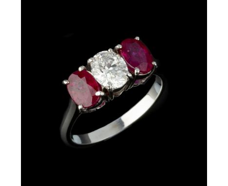 A three stone diamond and ruby ring, the central oval cut diamond, estimated to weigh 0.79 carats, between two oval cut rubie