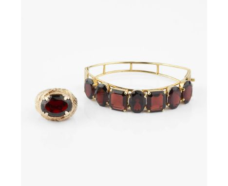 A 1960s garnet hinged bangle, the panel set with oval cut and step cut garnets with canted corners, stamped 18ct, 6.5cm wide,