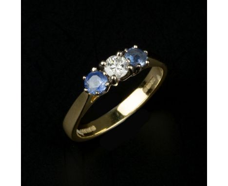 An 18 carat gold diamond and sapphire three stone ring, the central brilliant cut diamond, estimated to weigh 0.15 carats, cl