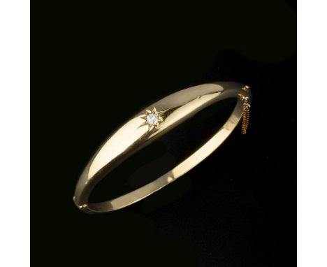 An Edwardian 18 carat gold diamond hinged bangle, the tapered front panel with a star set old cut diamond, estimated to weigh