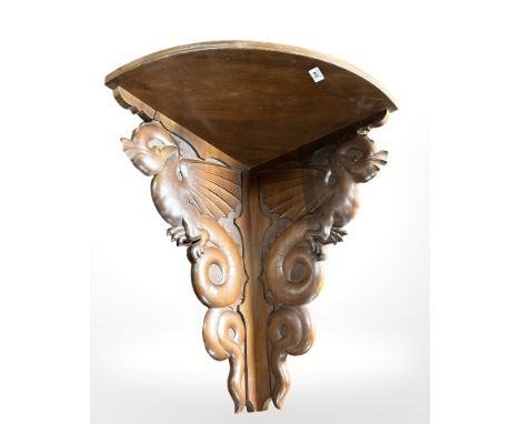 A carved walnut corner shelf decorated with dragons, length 65 cm.