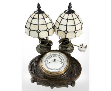 A carved oak barometer and a small pair of Tiffany-style table lamps.