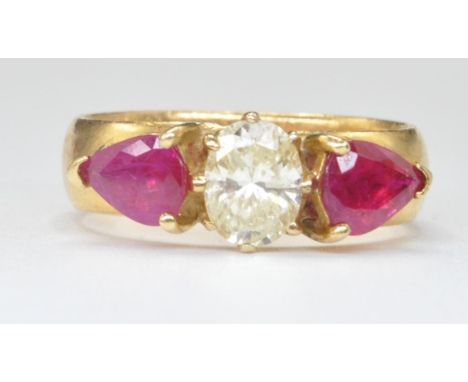 A 22ct gold ring set with a central oval cut diamond flanked by two pear cut rubies. Central diamond measures approx 7mm x 5m