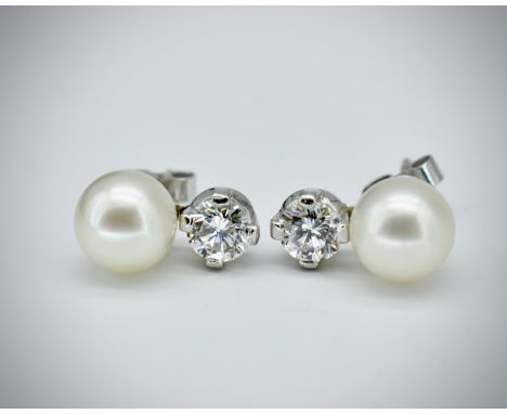 A pair of hallmarked 18ct gold pearl and diamond earrings. The earrings having a round brilliant cut diamond surmounted by pe