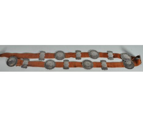 A 20th Century Navajo Native American belt having a suede belt threaded with seven round silver concho's and seven smaller si