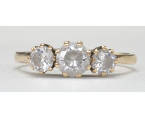 A hallmarked 9ct gold three stone ring having a central round cut white stone flanked by two smaller white stones in prong se