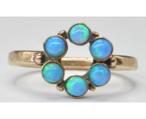 A 20th Century gold and opal ring set with a circle of six round cabochons to the head. Gold unmaked but tests indicate 9ct. 