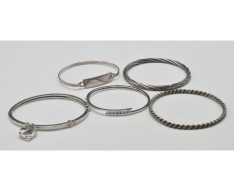 A group of five silver bangle bracelets to include a wrap around bangle set with white stones, a bangle with mother of pearl 