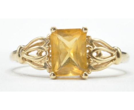 A hallmarked 9ct gold ring set with a central rectangular cut yellow stone with decorative pierced shoulders. Hallmarked Birm