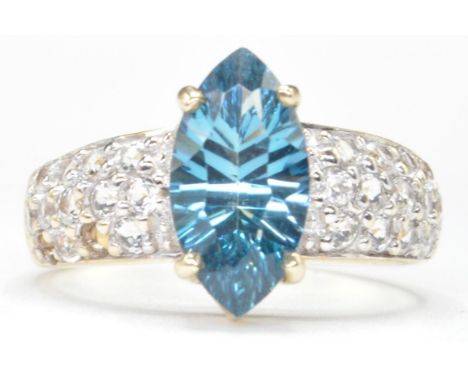 A hallmarked 9ct gold ring set with a central marquise cut blue topaz with three rows of round cut white stones to each shoul