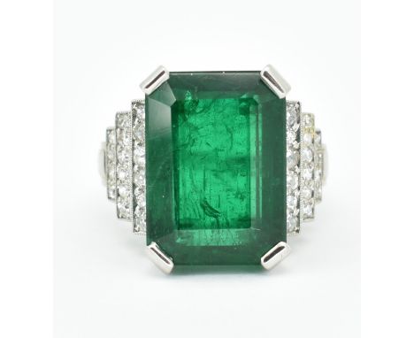 A platinum, emerald and diamond ring. The ring set with a large Octagon cut emerald flanked by terraced set round brilliant c