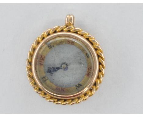 A 9ct gold case compass charm / pendant having a glass panelled centre with spinning hand and directions to the chapter ring 