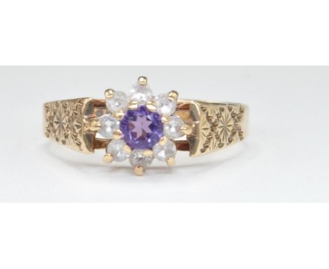 A 9ct gold and amethyst cluster ring. The ring with central&nbsp; round cut amethyst within a halo of cz stones. Set to a cha