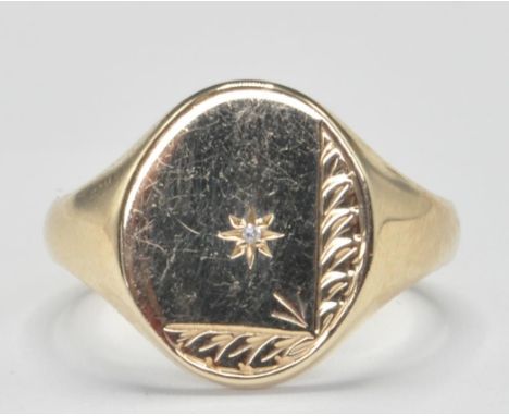 A hallmarked 9ct gold signet ring having an oval head set with a central round cut diamond with engraved decoration to the he