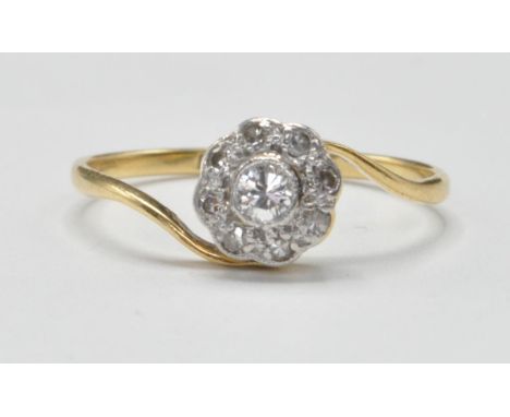 An 18ct gold and platinum diamond cluster crossover ring having a round head set with a central brilliant cut diamond with a 